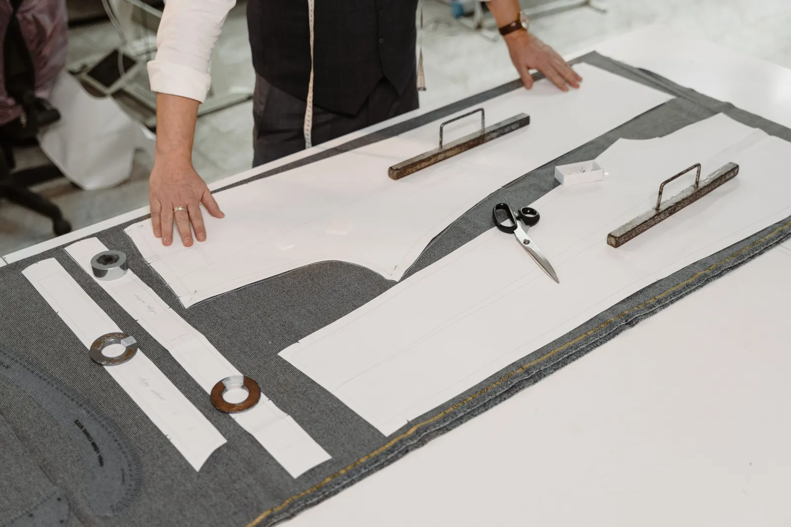 Moldes de papel sobre tecido plano na mesa de corte de uma confecção
