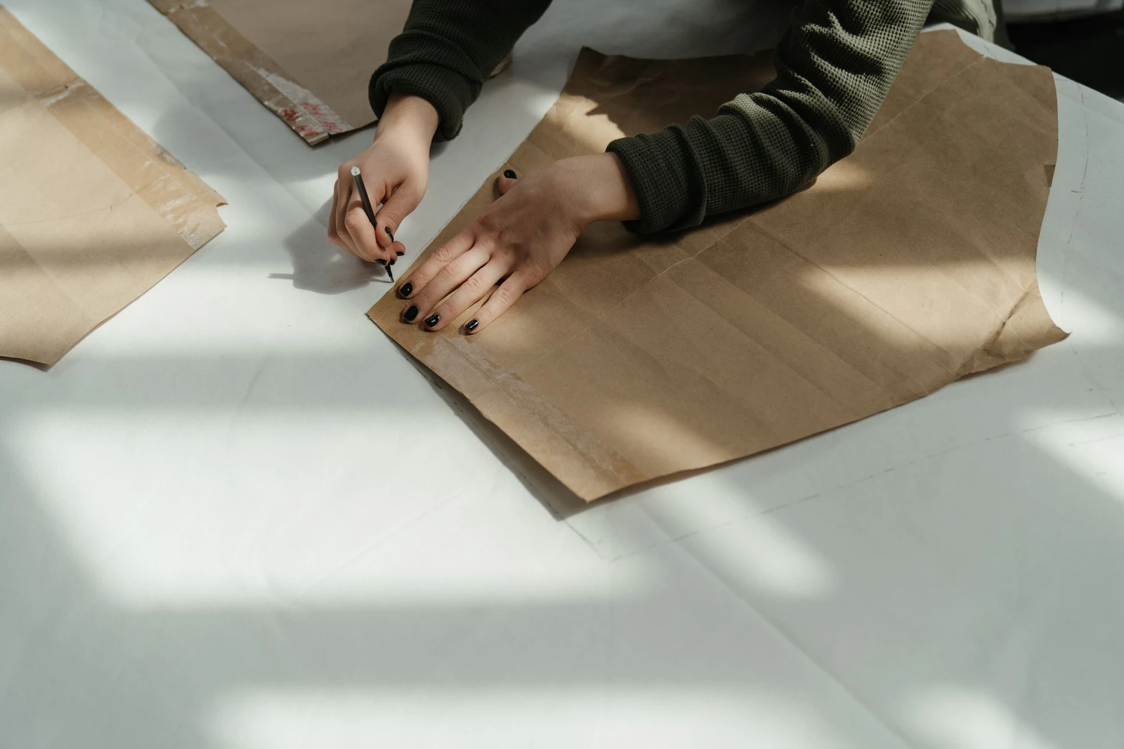 Mãos traçando moldes de papel de várias partes sobre a mesa de modelagem