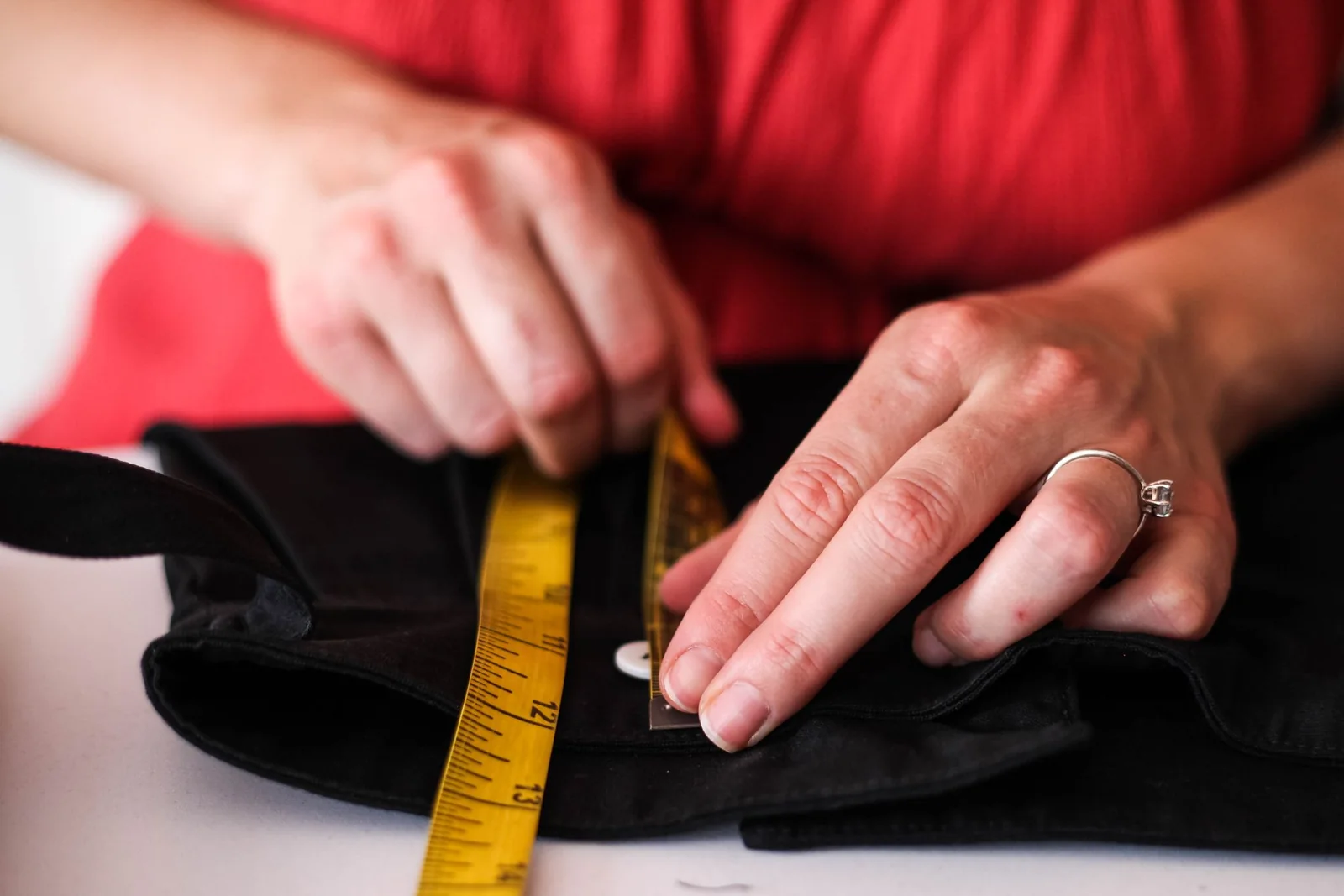 Fita métrica e régua sobre peça de roupa na mesa de conferência