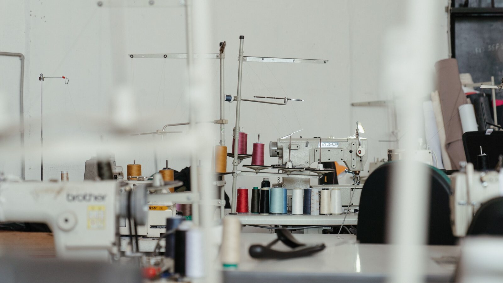 Oficina de costura industrial com máquinas e cones de linha